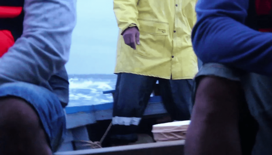 Three obscured figures ride in a boat over rough seas